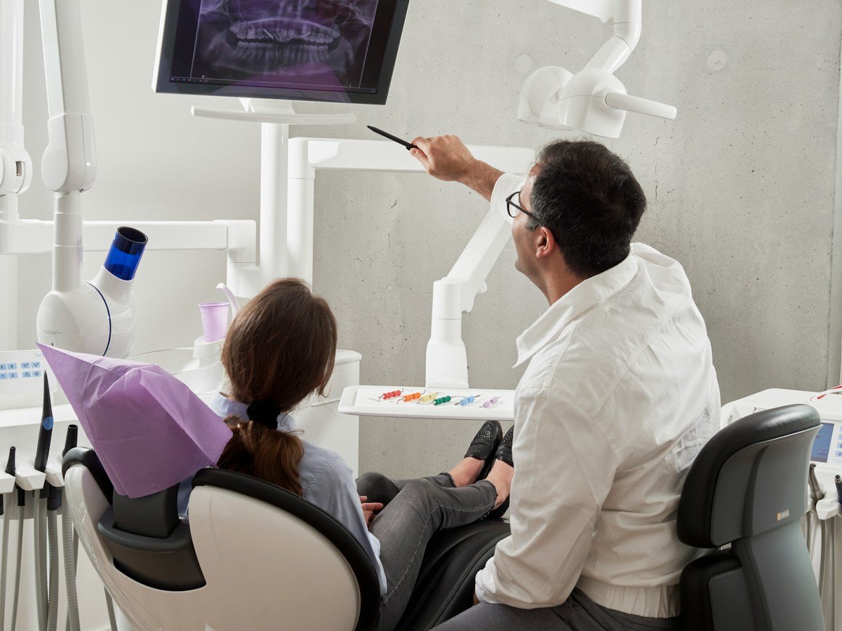 A dentist showing a patient her X-rays on a screen